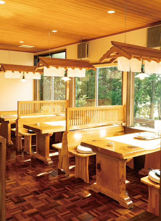 木の温もりを感じる麺屋 桜美の店内。窓から緑を望めるテーブル席が並ぶ